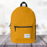 American Nostalgia Classic Simple Minimal Mustard Printed Backpack<br><div class="desc">This american nostalgia style classic backpack in mustard yellow features a patch style emblem with a monogram name and framed border,  featuring informal handwritten script and modern block typography. The text can be customised with your name for a design as unique as you are!</div>