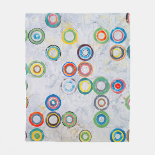 An abstract painting; multicolored circles on a gr fleece blanket