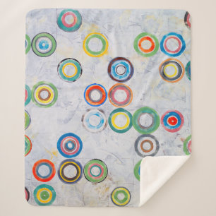 An abstract painting; multicolored circles on a gr sherpa blanket