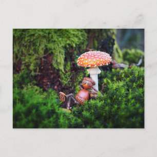 An acorn elf is resting under a mushroom postcard