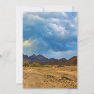 An arid landscape under a dramatic, cloudy sky holiday card