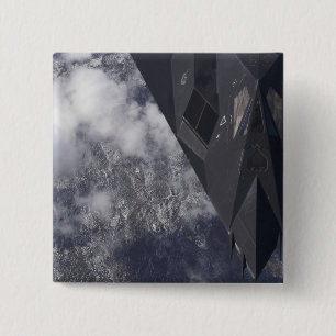 An F-117A Nighthawk flies high over the mountai 15 Cm Square Badge