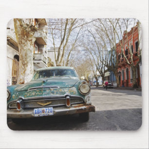 An old car rusty and flaky colour parked in the mouse mat