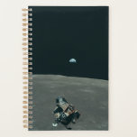 Apollo Lunar Lander and Earthrise Over Moon     Planner<br><div class="desc">The cramped command module served as a temporary home, framing a breathtaking vista. In the foreground, the delicate spider-like Lunar Module dangled, awaiting its descent. Beyond it stretched the stark, cratered moonscape, its horizon curving dramatically. But stealing the show was Earth, a vibrant blue marble suspended in the black abyss,...</div>