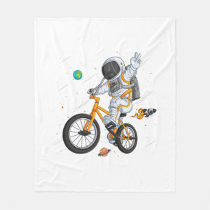 astronaut in spacesuit riding bmx bike on space ov fleece blanket