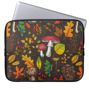Autumn mushrooms, leaves, nuts and berries on dark laptop sleeve