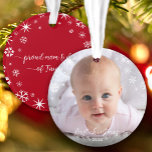 Baby Photo First Christmas Snowflakes New Parents Ornament<br><div class="desc">“First Christmas.” A playful visual of white snowflakes and handwritten script typography with customised year, overlaying the photo of your choice, help you usher in Christmas and New Year. On the back, additional white snowflakes and handwritten typography with “proud mum & dad of baby’s name” overlay a red background. Feel...</div>