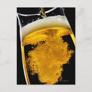 Beer been poured into glass, studio shot postcard