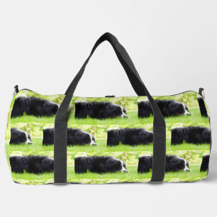 bernese mountain dog laying in grass duffle bag