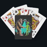Bigfoot Meets Alien Playing Cards<br><div class="desc">This whimsical image illustrates a friendly encounter between two legendary beings: Bigfoot and an alien. The scene, set against a starry night sky with silhouettes of pine trees, shows Bigfoot and the alien shaking hands under the beam of a UFO hovering above. Bigfoot, covered in brown fur, stands on the...</div>