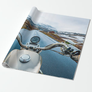 Biker rides a motorcycle on a slippery road throug wrapping paper