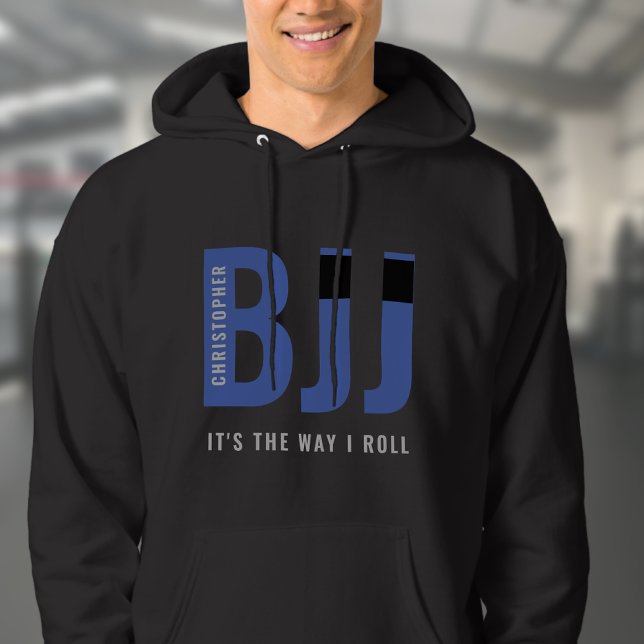 BJJ Brazilian Jiu Jitsu Add Name Blue Belt Hoodie (Blue Belt BJJ black hoodie worn by a male model in a gym.  )