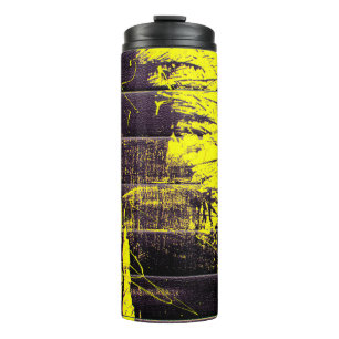 Black abstract splatter paint drips on a bright ye thermal tumbler