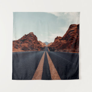 BLACK ASPHALT ROAD BETWEEN BROWN ROCK FORMATION UN TAPESTRY