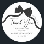 Black bow she's tying the knot bridal shower classic round sticker<br><div class="desc">Host an unforgettable bridal shower with this elegant "She's Tying the Knot" sticker featuring a stylish black bow design. Perfect for a modern black-and-white theme, this sticker blends chic sophistication with timeless charm. Fully customisable, it allows you to easily update the bride's name, event date, location, and other details to...</div>