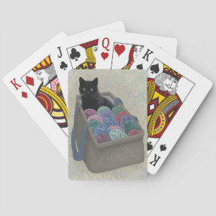 Black cat in yarn bag playing cards