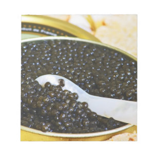 Black caviar and a spoon of mother-of-pearl to notepad