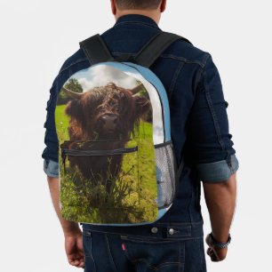 Black highland cow grazing green field sun light printed backpack