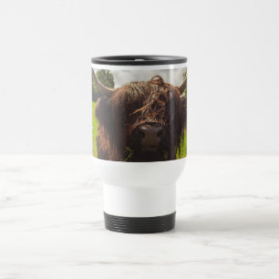 Black highland cow grazing green field sun light travel mug