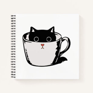 Black kitten with red nose hiding in a cup notebook