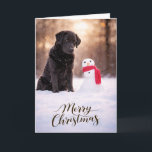 Black Labrador Christmas Snowman Card<br><div class="desc">A heartwarming Christmas card featuring a loyal Black Labrador sitting in fresh winter snow beside a cheerful little snowman wrapped in a red scarf. Warm golden winter light and softly falling snow create a peaceful holiday moment that captures the gentle spirit and faithful companionship Labrador Retrievers are known for. Perfect...</div>