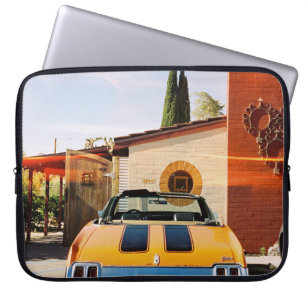 Blue car parked beside brown concrete building in laptop sleeve