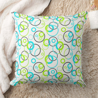 blue green and black rings and circles on white cushion