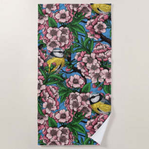 Blue tit birds in the blooming cherry tree on blue beach towel