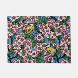 Blue tit birds in the blooming cherry tree on blue doormat