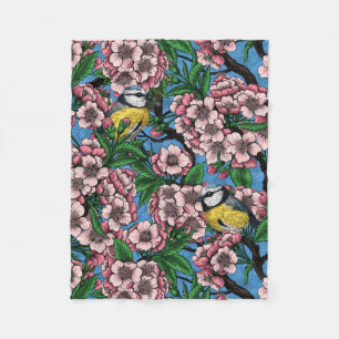 Blue tit birds in the blooming cherry tree on blue fleece blanket