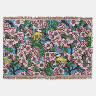 Blue tit birds in the blooming cherry tree on blue throw blanket