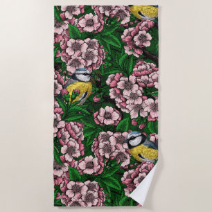 Blue tit birds in the blooming cherry tree on gree beach towel