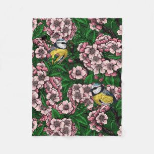 Blue tit birds in the blooming cherry tree on gree fleece blanket