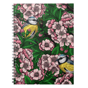 Blue tit birds in the blooming cherry tree on gree notebook