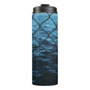 Body of water in front of chain link fence thermal tumbler