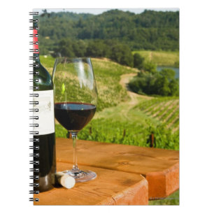 Bottle of red wine and glass on table notebook