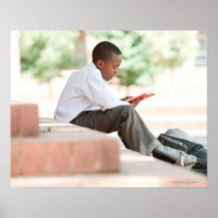 Boy reading on steps outside school, poster