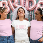 Bride T-Shirt | Personalised Future Mrs. Name<br><div class="desc">This modern and personalised Bride T-Shirt is the perfect outfit for any bride-to-be! Featuring soft blush pink “BRIDE” text paired with elegant handwritten “future Mrs. [Your Name]” below, this tee is ideal for bridal showers, bachelorette parties, wedding prep, and honeymoon travel. Available in multiple styles and fits for every bride’s...</div>