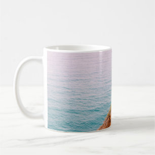 Brown rock mountain on body of water coffee mug