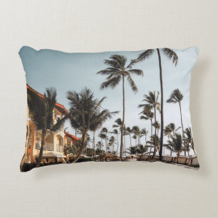 Brown wooden lounge chairs near pool surrounded by decorative cushion