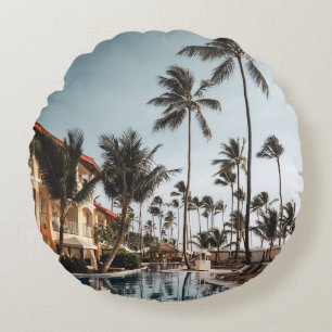 Brown wooden lounge chairs near pool surrounded by round cushion