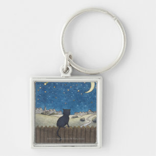 Cat on a fence looking at night sky above city key ring