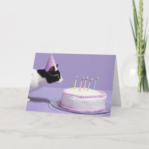 Cat wearing birthday hat blowing out candles card