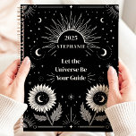 Celestial Sun Moon Stars Custom Manifestation  Planner<br><div class="desc">This captivating design features celestial elements such as the sun, moon, stars, and blooming sunflowers, all set against a bold black background. The motivational phrase "Let the Universe Be Your Guide" inspires focus and manifestation, making this design both functional and empowering. Personalised with a custom name and year, it’s perfect...</div>
