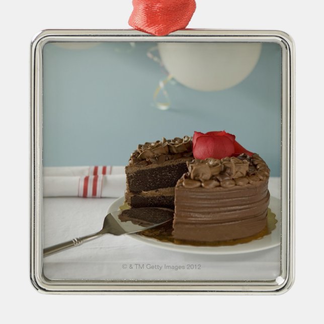 Chocolate cake with missing slice on table, metal tree decoration (Front)