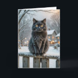 Christmas Black Cat On a Snowy Fence Card<br><div class="desc">A fluffy black cat with striking yellow eyes sits atop a snow-dusted wooden fence,  surrounded by a picturesque winter village.
All text can be changed.</div>
