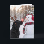Christmas Black Labrador Retriever with Snowman Card<br><div class="desc">A black Labrador retriever with a glowing red nose and reindeer antlers stands beside a snowman in a winter forest.
The inside text can be changed.</div>