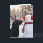 Christmas Black Labrador Retriever with Snowman Card<br><div class="desc">A black Labrador retriever with a glowing red nose and reindeer antlers stands beside a snowman in a winter forest.
The inside text can be changed.</div>
