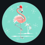 Christmas Flamingo sticker round<br><div class="desc">Stylish design with a retro touch featuring a festive pink flamingo wearing a red Santa hat, stars and palm trees decorated with baubles set against an aqua background. A customisable design for you to personalise with your own text, images and ideas. An original digital art image created by Quirky Chic....</div>