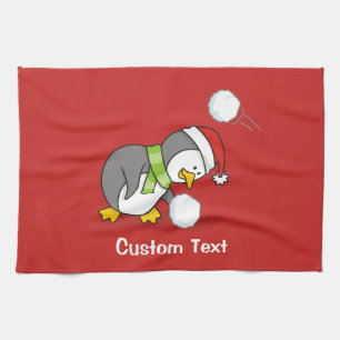 Christmas penguin getting a snow ball tea towel